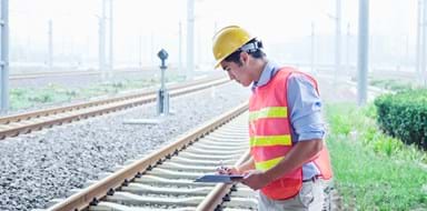 Railroad worker in protective work wear checking the railroad tracks
