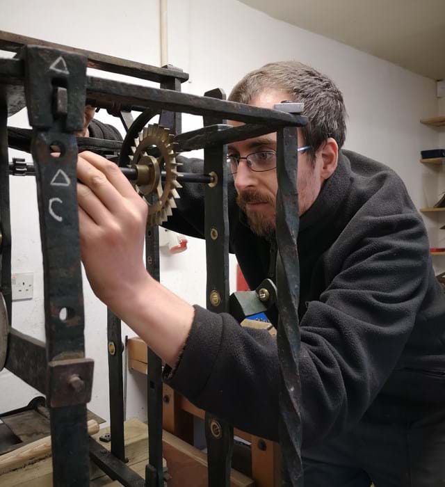 Engineer inspecting and restoring a mechanical clock