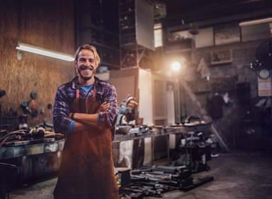 Portrait of smiling mechanic standing in garage workshop with professional equipment