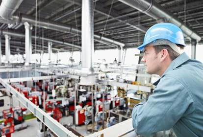 Factory-worker in hard-hat looking at factory floor