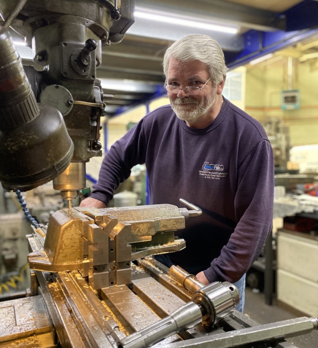 Engineer working on machinery looking at camera inside MachFab
