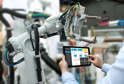A person controlling a robotic arm with a tablet. 