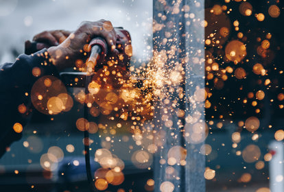 Industrial Worker wearing protective equipment, grinding steel in workshop