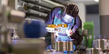 Factory worker using a welding torch to fabricate metal