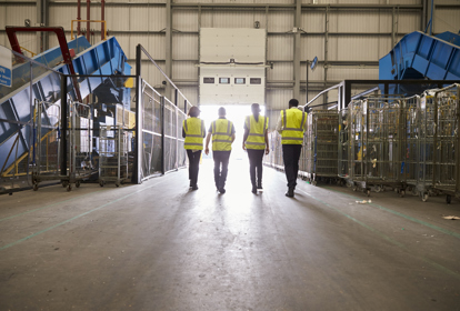 Four colleagues in reflective vests leaving a warehouse