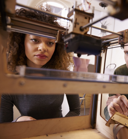 Two Designers Working With 3D Printer In Design Studio