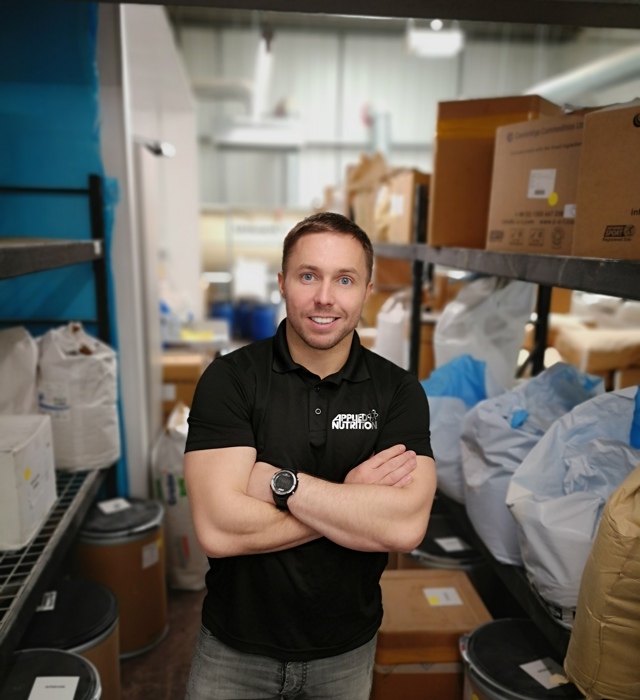 Senior leader at Applied Nutrition stood in factory looking at the camera