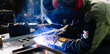 Industrial engineer using blow torch to weld metal work