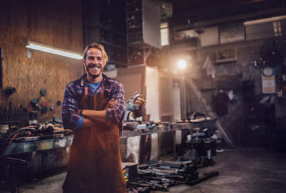 Portrait of smiling mechanic standing in garage workshop with professional equipment