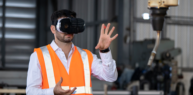 Male factory worker operating a robotic arm using a virtual reality headset