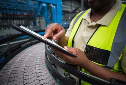 Mid section of factory worker using digital tablet in the factory