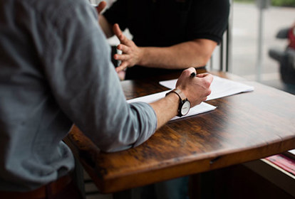 People sat at desk discussing work with pen and paper